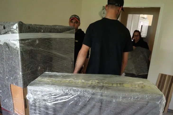 umzugshelfer transportieren verpackte moebel im wohnraum